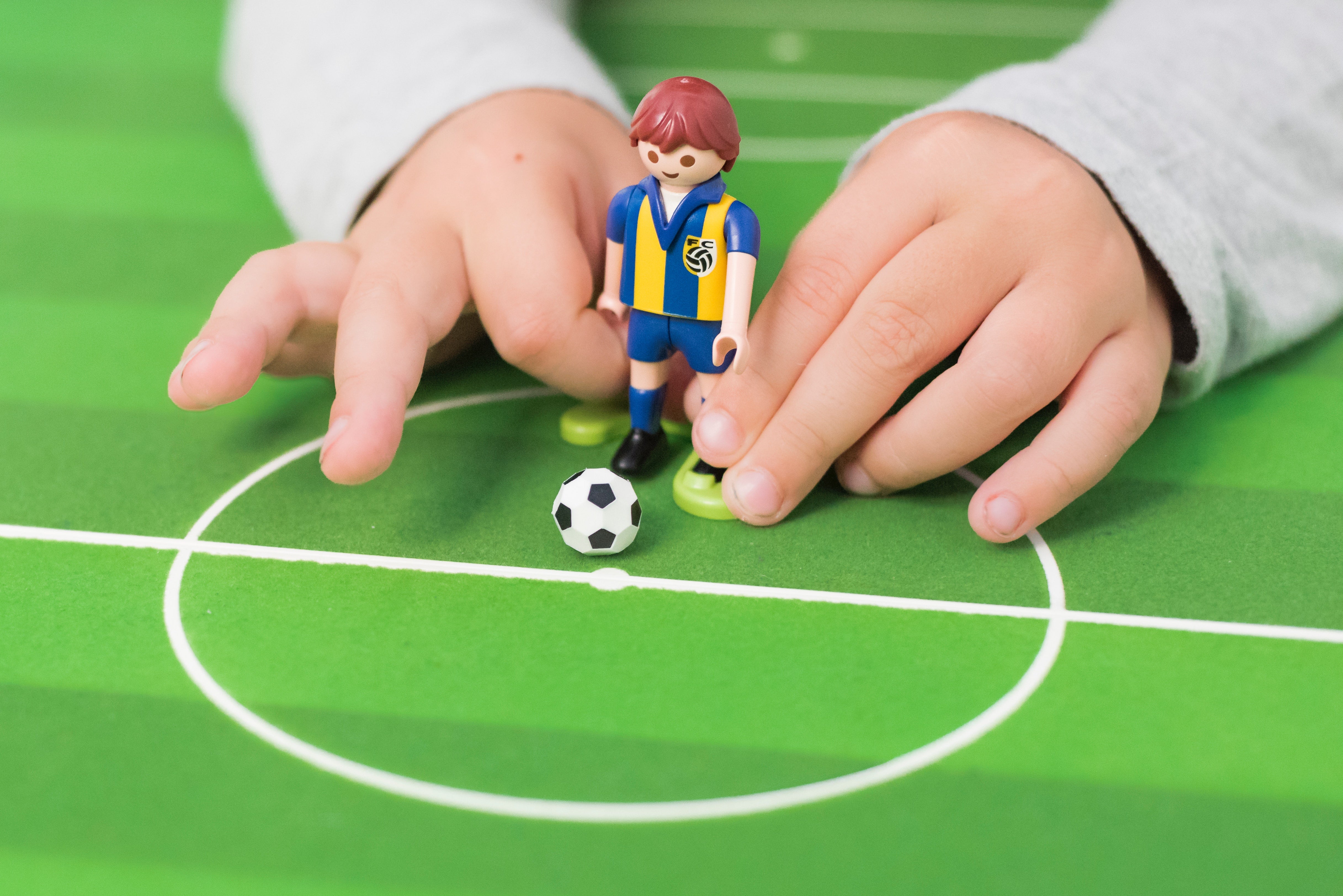 a kid hand playing lego that is about to kick the ball 